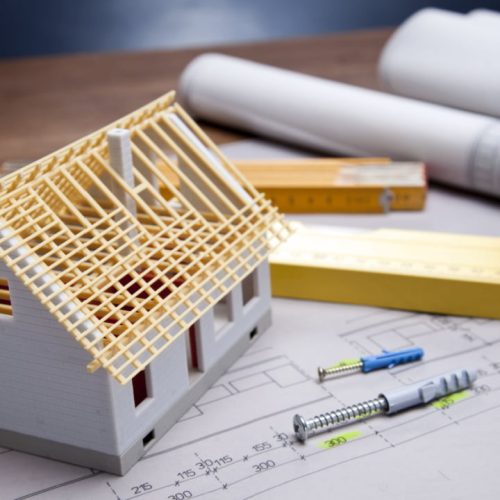 modelo de casa en construcción sobre planos arquitectónicos con herramientas de medición, concepto de diseño y planificación de viviendas." Este texto es descriptivo y contiene palabras clave relevantes para el sector de arquitectura, construcción y diseño de viviendas, ayudando a posicionar mejor la imagen en buscadores